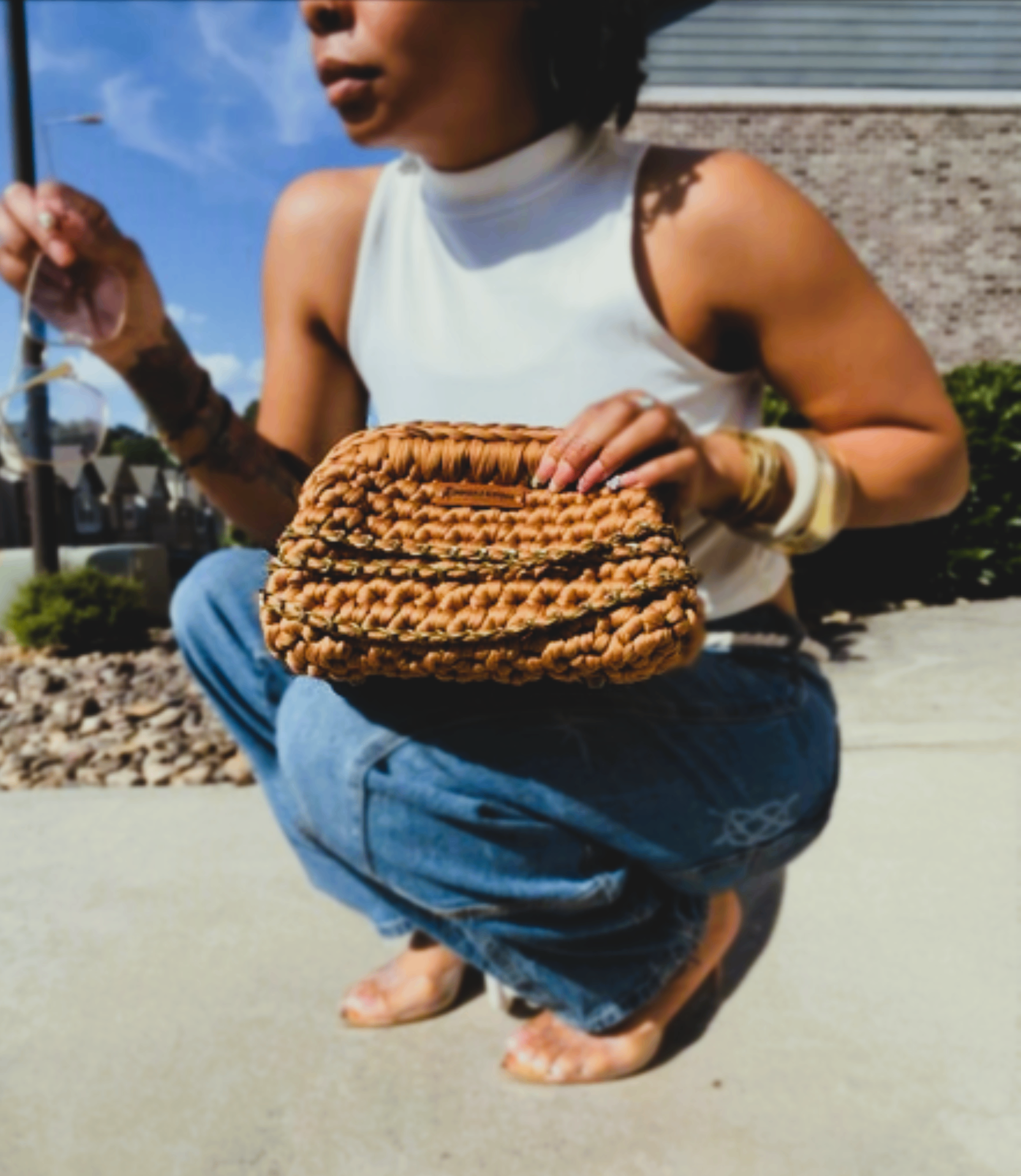Woman holding a tan crochet clutch outdoors
